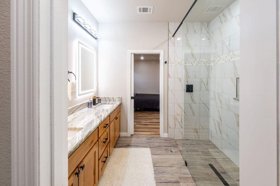Bathroom with vanity, hardwood / wood-style flooring, and a tile shower