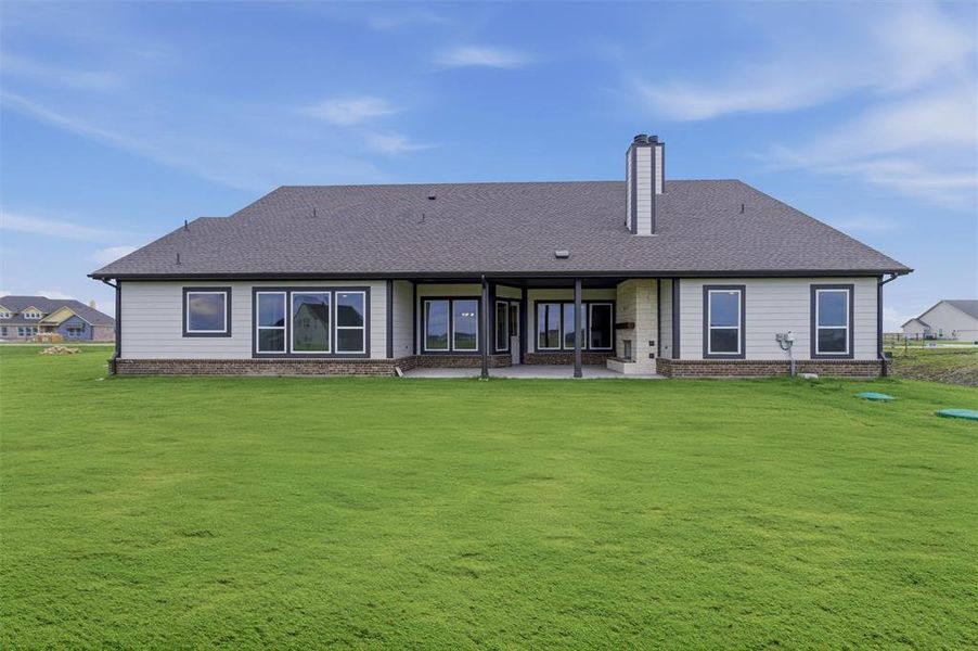 Expansive green lawn surrounds a contemporary residence with a covered patio