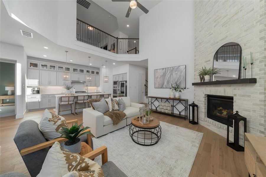 Living room with ceiling fan, light wood-type flooring, a fireplace, and visible vents