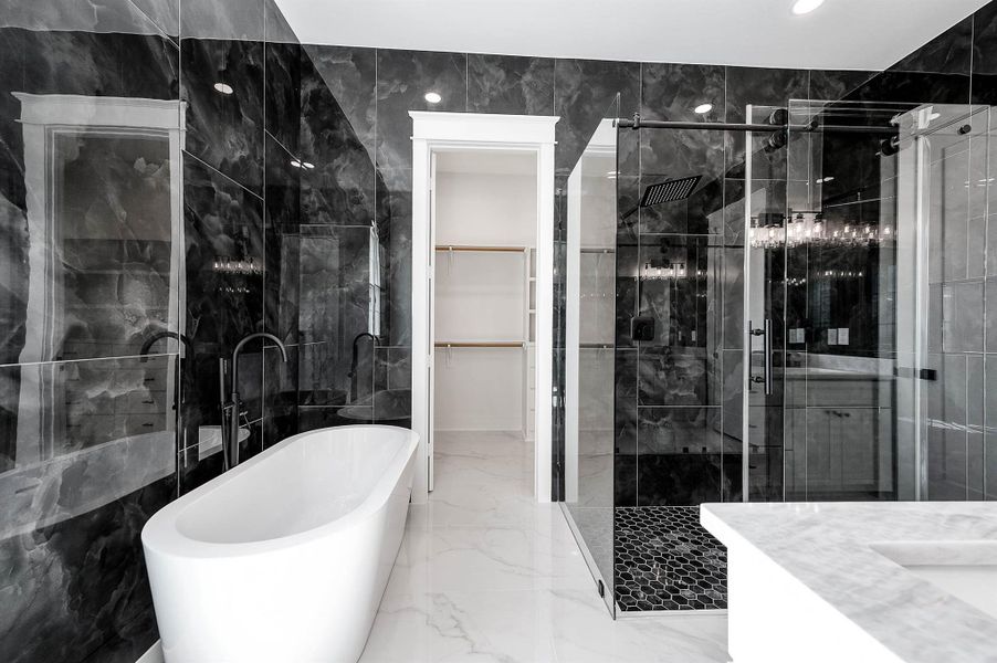 Luxury primary bathroom featuring a freestanding tub, double-sink vanity, bold floor-to-ceiling tile, and a spacious glass-enclosed shower with dual shower heads. Luxury primary bathroom featuring a freestanding tub, double-sink vanity, bold floor-to-ceiling tile, and a spacious glass-enclosed shower with dual shower heads.