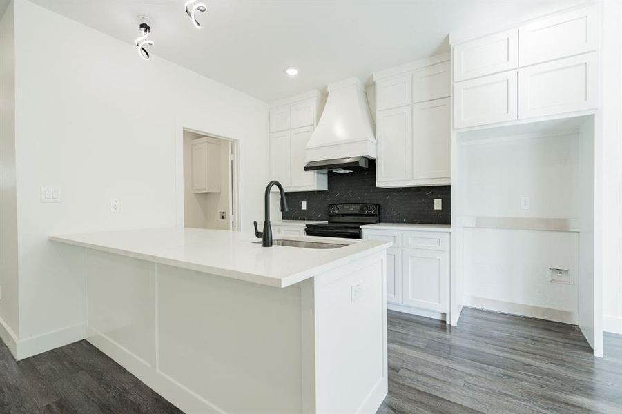 Kitchen with tasteful backsplash, dark wood-type flooring, custom range hood, black range with electric stovetop, and white cabinets