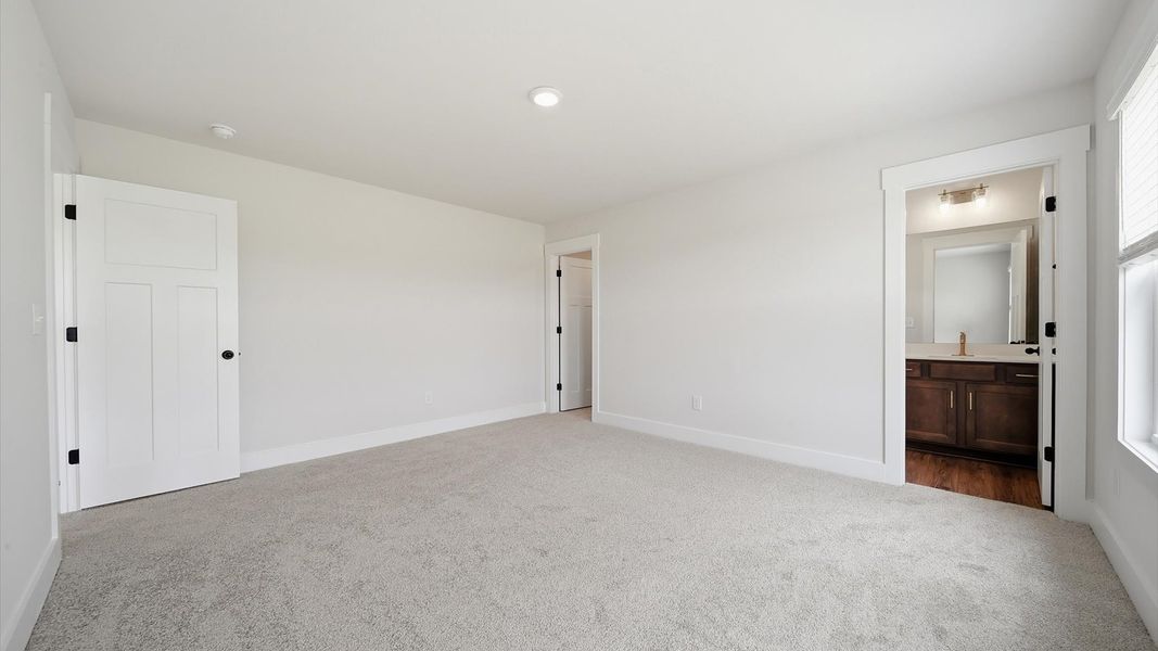 Elegant bedroom retreat featuring soft carpeting and a thoughtfully designed walk-in closet by DRB Homes