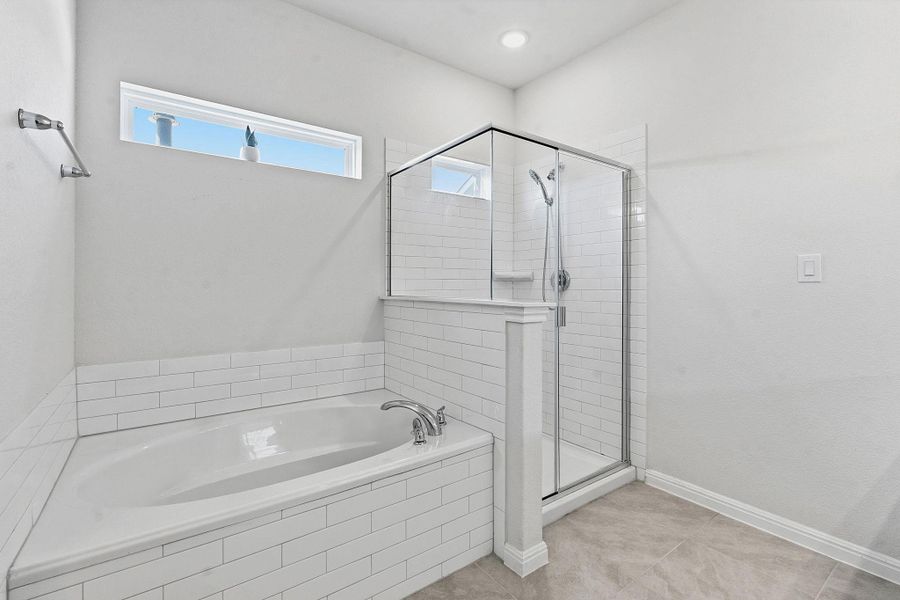 A well-lit primary bathroom provides a spacious walk-in shower alongside a soaking tub for ultimate relaxation. A well-lit primary bathroom provides a spacious walk-in shower alongside a soaking tub for ultimate relaxation.