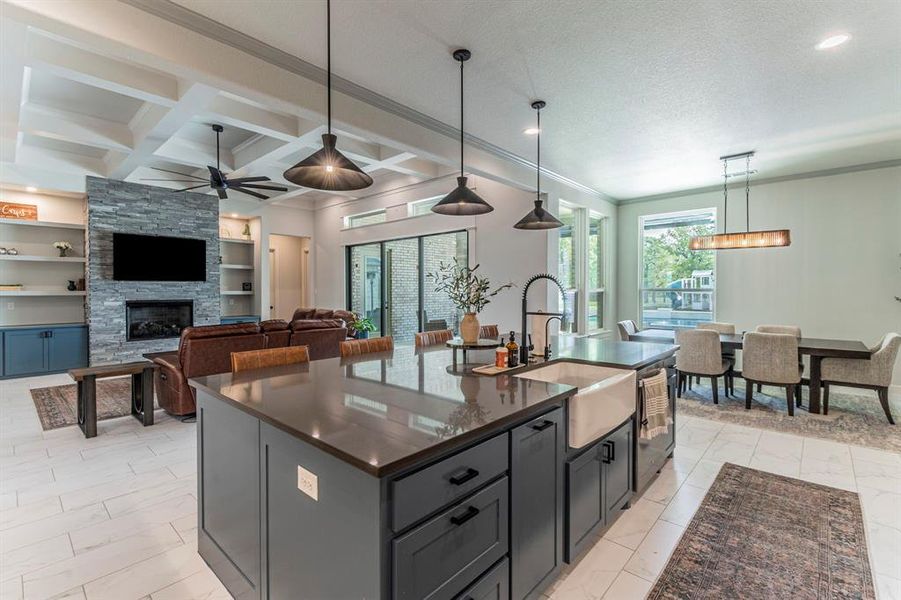 Kitchen with open floor plan, a center island with sink, decorative light fixtures, dark stone countertops, and ornamental molding Kitchen with open floor plan, a center island with sink, decorative light fixtures, dark stone countertops, and ornamental molding