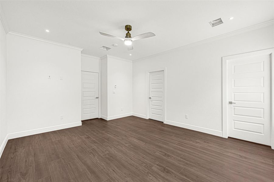 This photo showcases a spacious room with sleek hardwood flooring, crisp white walls, and modern recessed lighting. The room features multiple doors with a contemporary design and a ceiling fan, offering a bright and versatile space ideal for any home buyer. This photo showcases a spacious room with sleek hardwood flooring, crisp white walls, and modern recessed lighting. The room features multiple doors with a contemporary design and a ceiling fan, offering a bright and versatile space ideal for any home buyer.