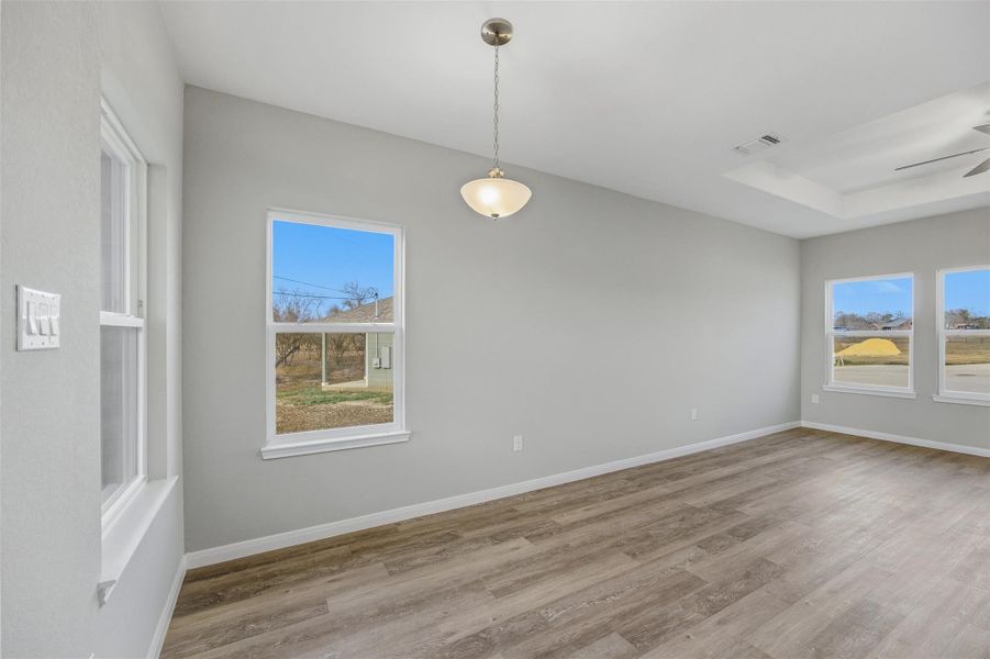 A clean, newly built interior features warm wood flooring and ample natural light from multiple windows.