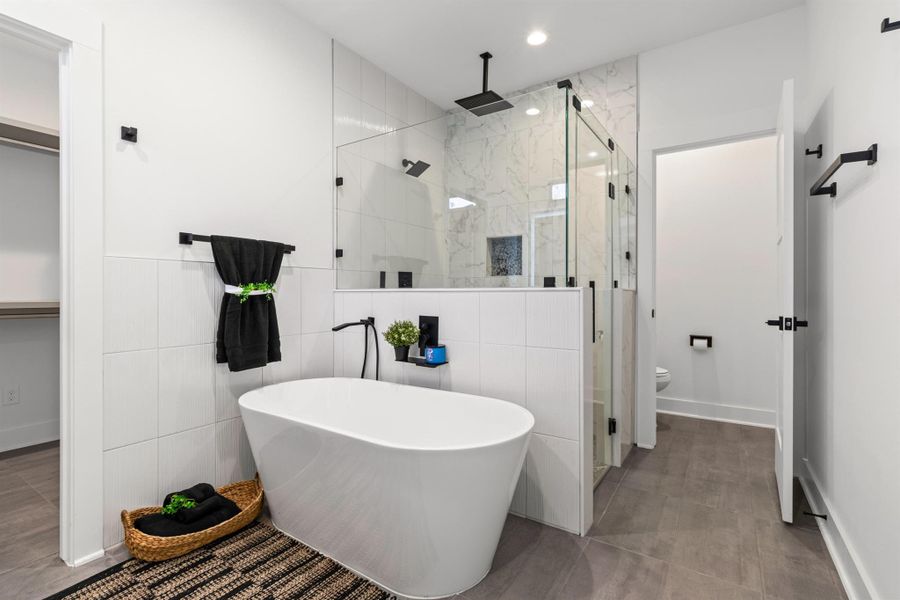 Full bath featuring a soaking tub, a marble finish shower, tile walls, and a walk in closet