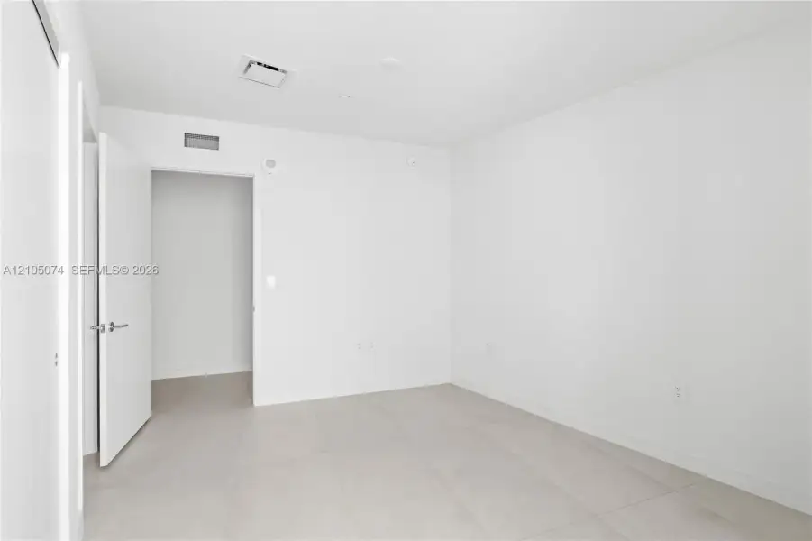Neutral-toned interior space featuring light-colored tile flooring and minimalist, crisp white walls