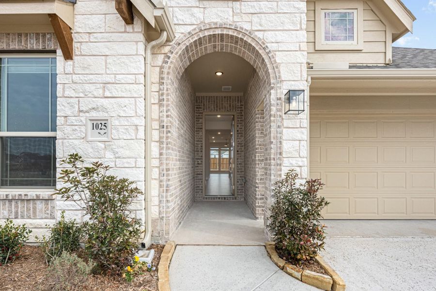 Home entrance with arched brick entryway, stone exterior, and two-car garage beside front door Home entrance with arched brick entryway, stone exterior, and two-car garage beside front door