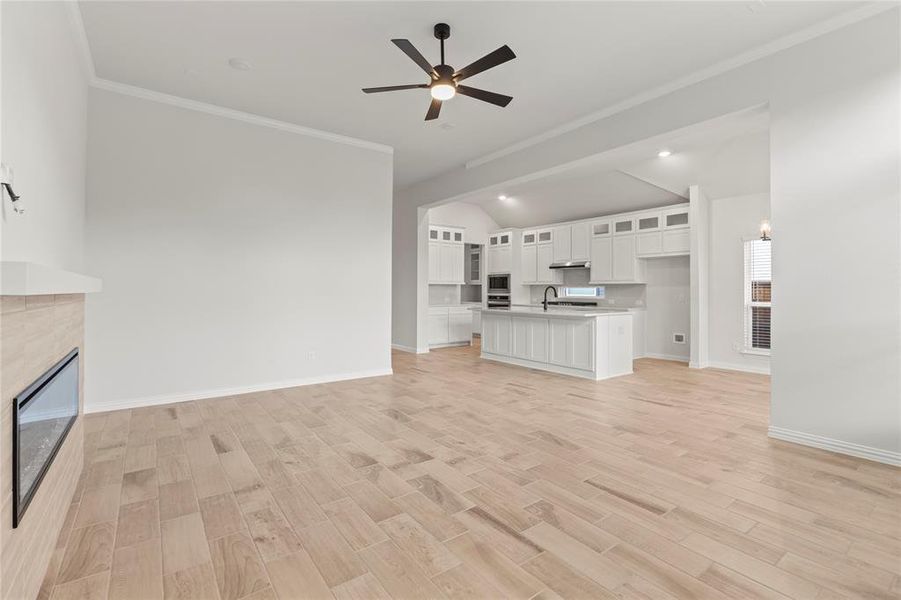 Unfurnished living room featuring sink, a fireplace, light hardwood / wood-style flooring, and vaulted ceiling