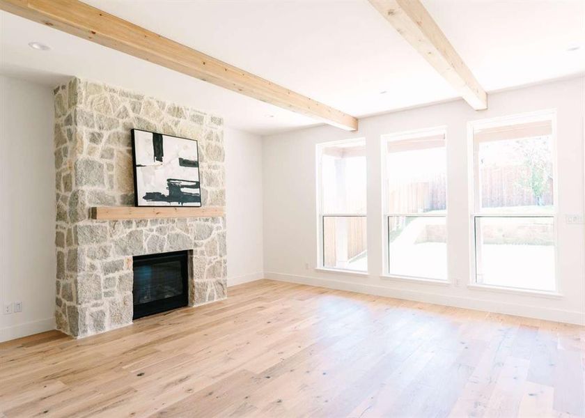 Unfurnished living room featuring beamed ceiling, light wood-type flooring, and a fireplace