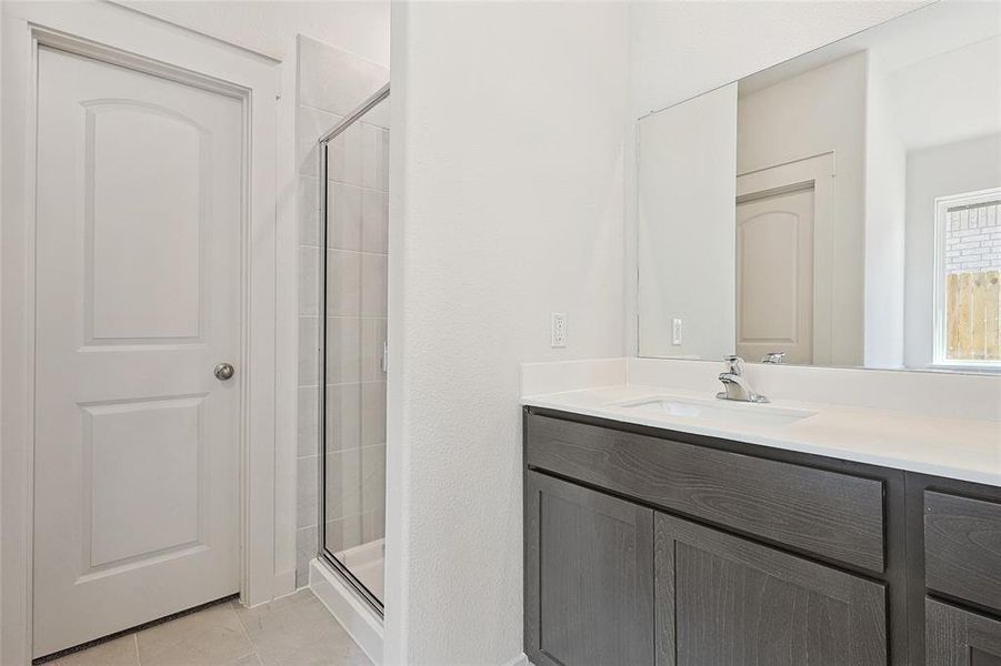 Bathroom with tile patterned floors, an enclosed shower, and vanity