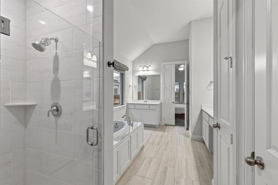 Full bathroom featuring a bath, vanity, ensuite bathroom, vaulted ceiling, and a shower stall Full bathroom featuring a bath, vanity, ensuite bathroom, vaulted ceiling, and a shower stall