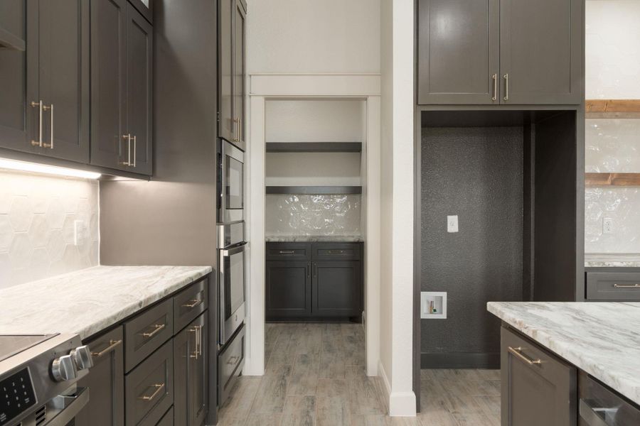 Kitchen featuring appliances with stainless steel finishes, backsplash, light stone countertops, light wood finished floors, and open shelves