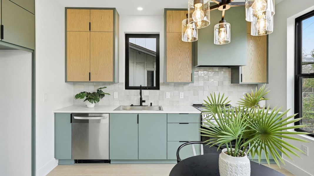 Kitchen featuring stainless steel dishwasher, range, tasteful backsplash, pendant lighting, and light wood-type flooring