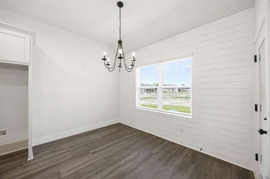 Room with wood-finish flooring and a white shiplap accent wall