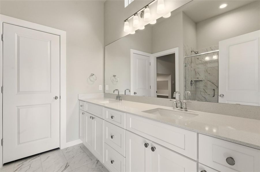 Bathroom with light marble finish floors, double vanity, and a marble finish shower