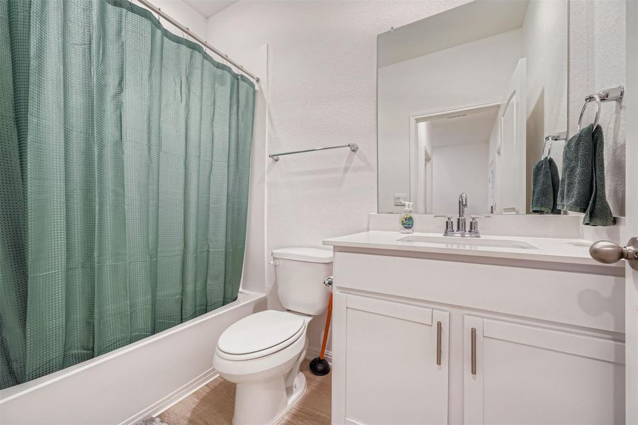 Full bath featuring shower / bathtub combination with curtain, vanity, and light wood-type flooring