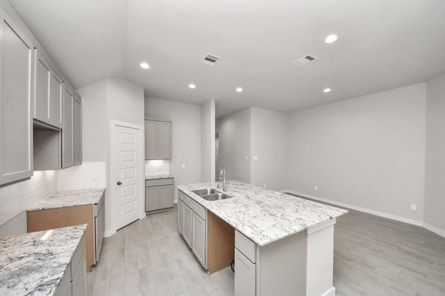 This generously spacious kitchen is a dream realized! With a massive granite island, high ceilings, soft close cabinets, granite countertops, stainless steel appliances, a sleek tile backsplash, recessed lighting, and an extended counter area, it offers both style and practicality. All this opens up to the expansive family room, creating a perfect hub for gatherings. Sample photo of completed home with similar floor plan. Actual colors and selections may vary. This generously spacious kitchen is a dream realized! With a massive granite island, high ceilings, soft close cabinets, granite countertops, stainless steel appliances, a sleek tile backsplash, recessed lighting, and an extended counter area, it offers both style and practicality. All this opens up to the expansive family room, creating a perfect hub for gatherings. Sample photo of completed home with similar floor plan. Actual colors and selections may vary.