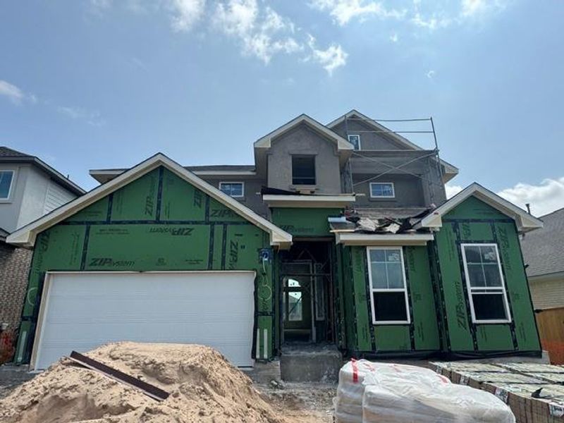 A newly framed residence, nearly ready for its finishing touches, stands tall against a clear sky.