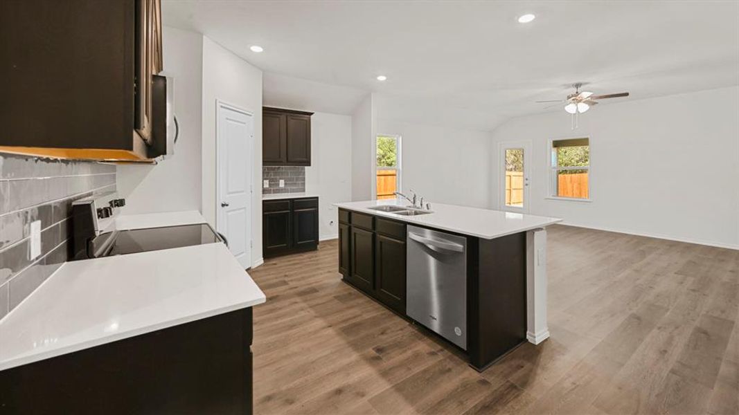 Open-concept kitchen and living area featuring dark wood-finish cabinetry, white countertops, stainless steel appliances, and wood-finish flooring throughout Open-concept kitchen and living area featuring dark wood-finish cabinetry, white countertops, stainless steel appliances, and wood-finish flooring throughout