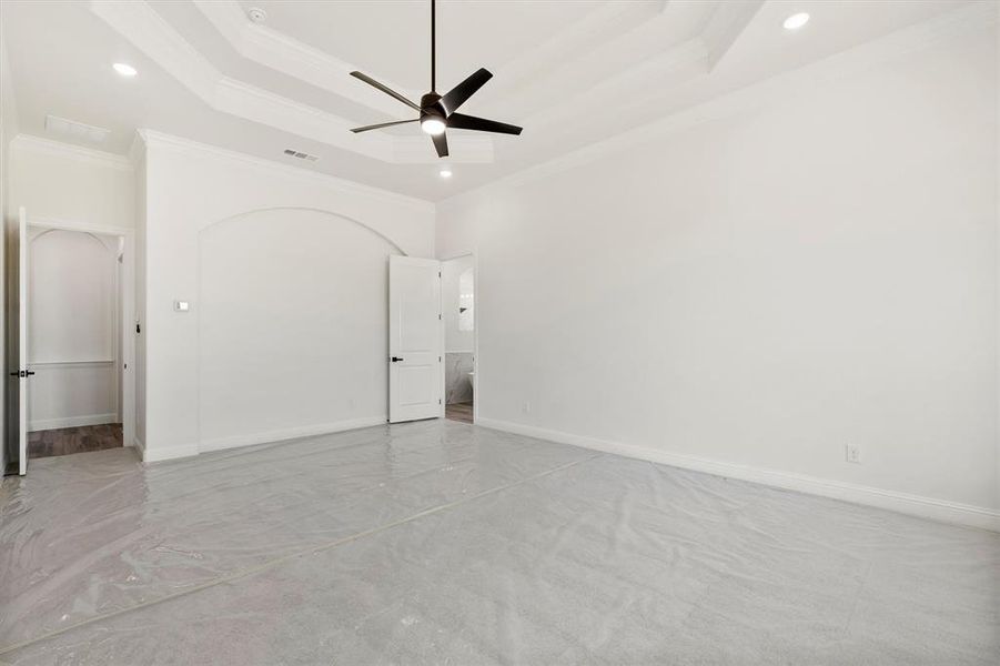 Master  room with ceiling fan, a tray ceiling, and ornamental molding