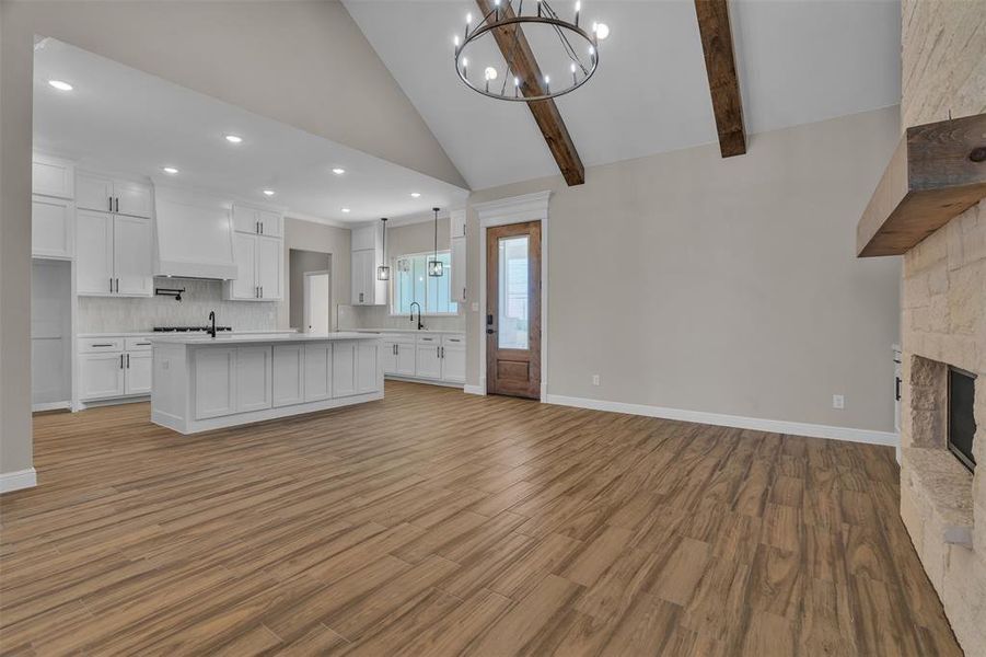 Kitchen with open floor plan, high vaulted ceiling, a chandelier, light countertops, and light wood finished floors Kitchen with open floor plan, high vaulted ceiling, a chandelier, light countertops, and light wood finished floors