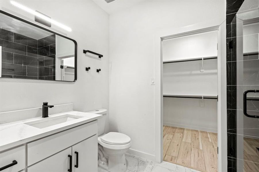 Bathroom featuring vanity, a walk in closet, toilet, and a shower stall Bathroom featuring vanity, a walk in closet, toilet, and a shower stall