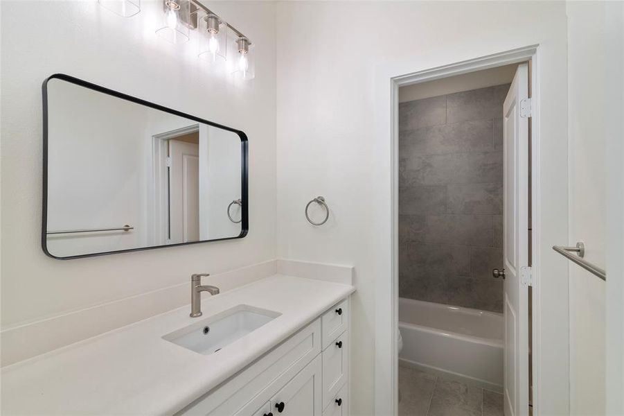 Full bathroom featuring toilet, vanity, tile patterned floors, and tiled shower / bath