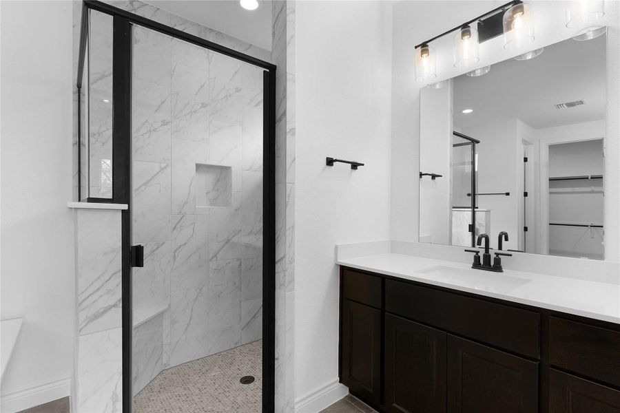 Bathroom with a marble finish shower, vanity, a walk in closet, and recessed lighting