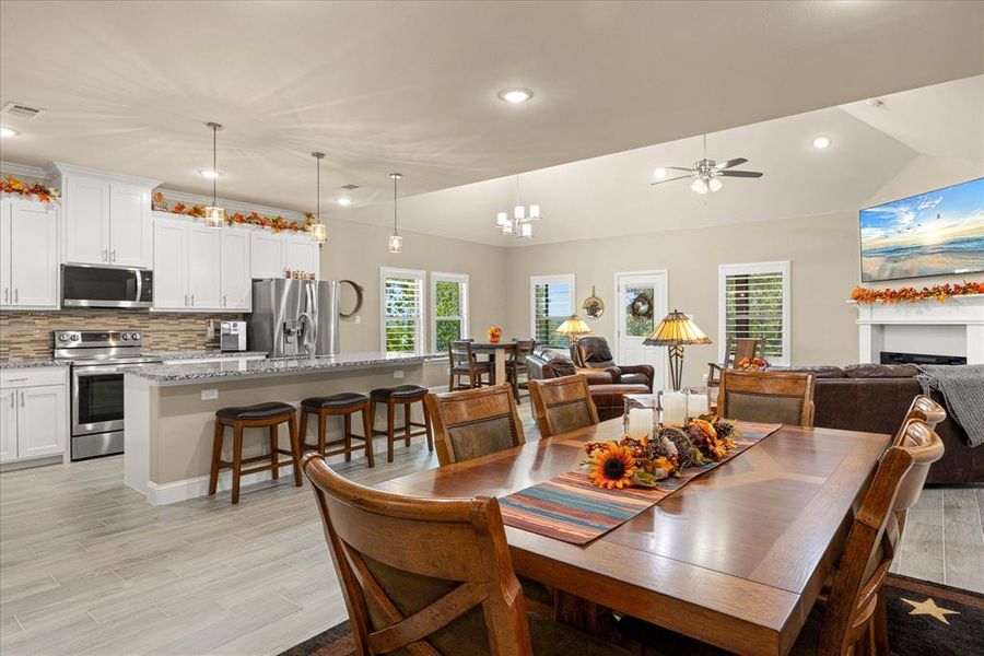 Dining area featuring recessed lighting, a fireplace, light wood-style flooring, lofted ceiling, and a ceiling fan Dining area featuring recessed lighting, a fireplace, light wood-style flooring, lofted ceiling, and a ceiling fan