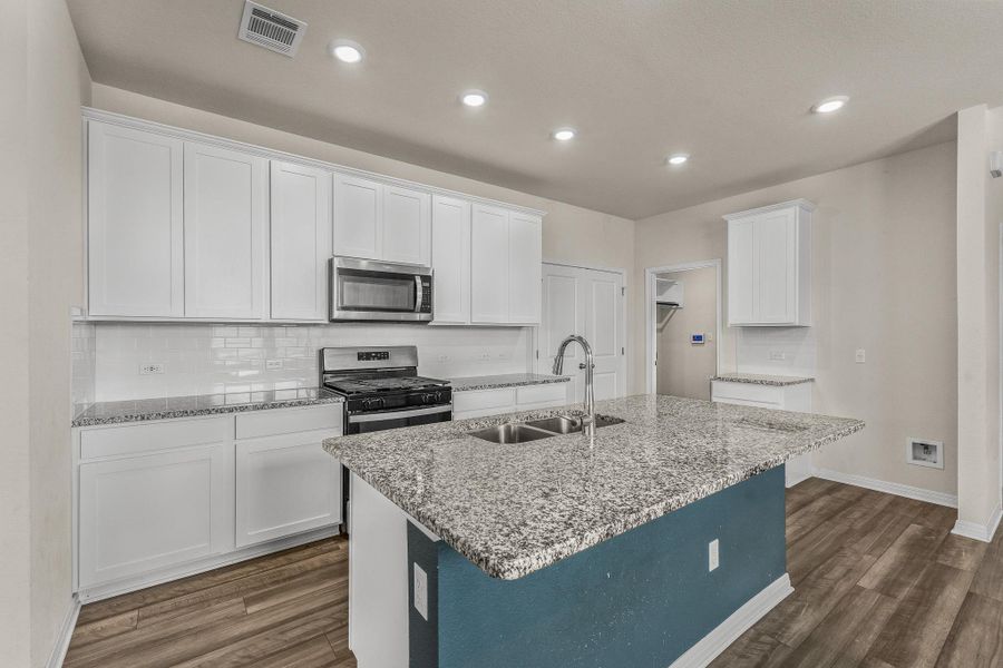 Kitchen with decorative backsplash, white cabinets, light stone countertops, dark wood-type flooring, and stainless steel appliances Kitchen with decorative backsplash, white cabinets, light stone countertops, dark wood-type flooring, and stainless steel appliances