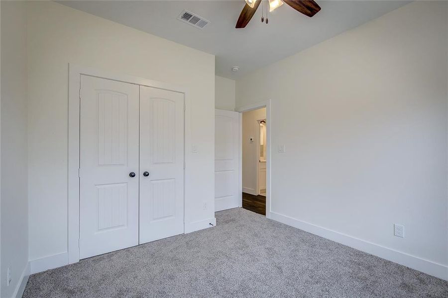 Unfurnished bedroom featuring carpet flooring, a closet, and a ceiling fan Unfurnished bedroom featuring carpet flooring, a closet, and a ceiling fan