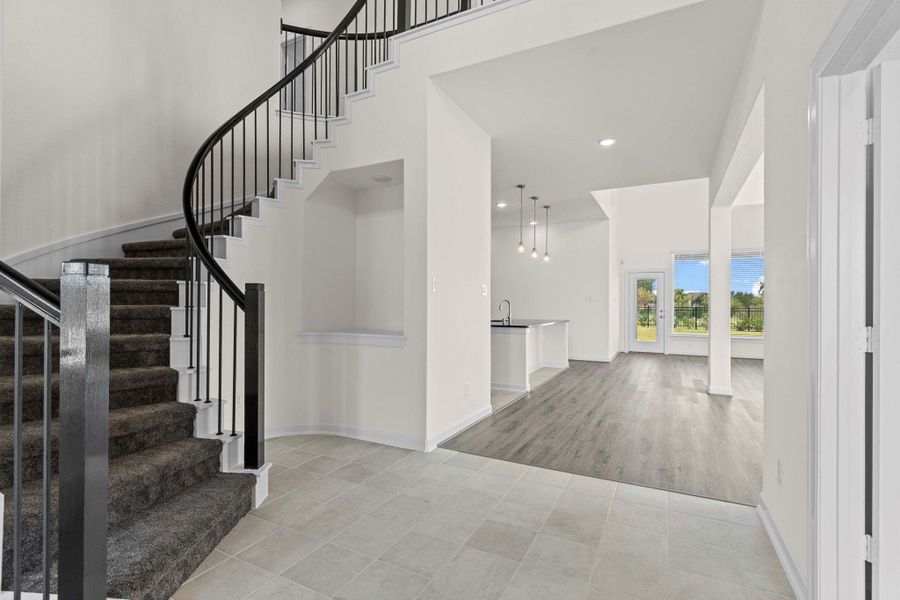 Dramatic view of the sweeping iron stairway with elegant wrought-iron railing, soaring ceilings, and open sightlines that connect the entry to the upstairs living spaces — a true architectural highlight of this home. Dramatic view of the sweeping iron stairway with elegant wrought-iron railing, soaring ceilings, and open sightlines that connect the entry to the upstairs living spaces — a true architectural highlight of this home.