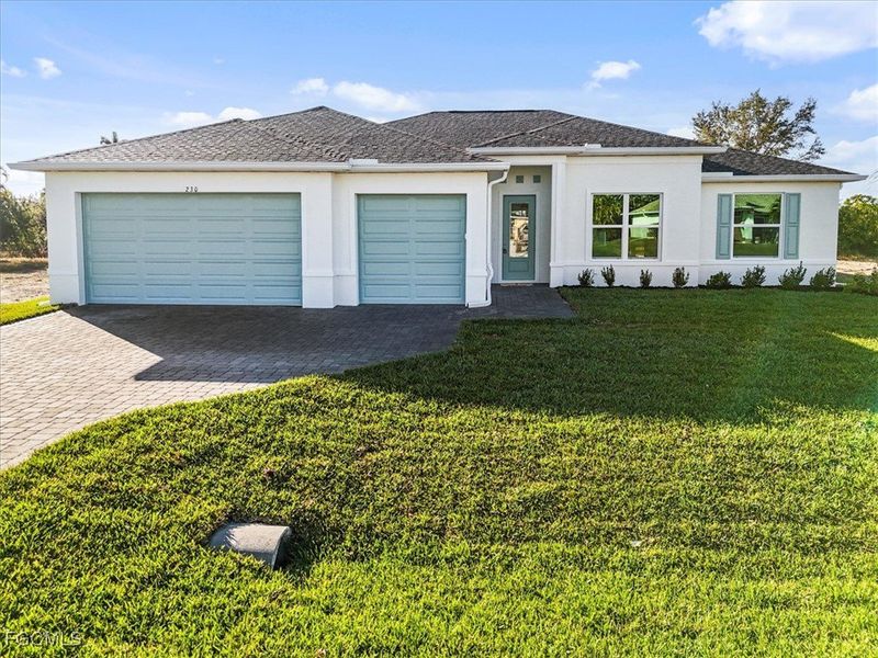 Prairie-style house with stucco siding, decorative driveway, a front lawn, and an attached garage