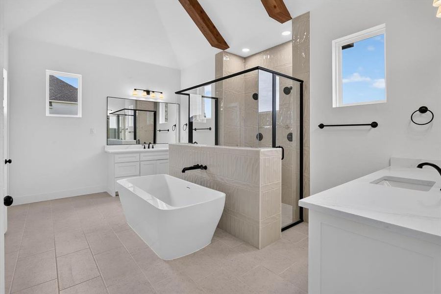 Spacious bathroom featuring a freestanding soaking tub, a large walk-in shower with black-framed glass enclosure, and dual vanity areas with white cabinetry and solid surface countertops Spacious bathroom featuring a freestanding soaking tub, a large walk-in shower with black-framed glass enclosure, and dual vanity areas with white cabinetry and solid surface countertops