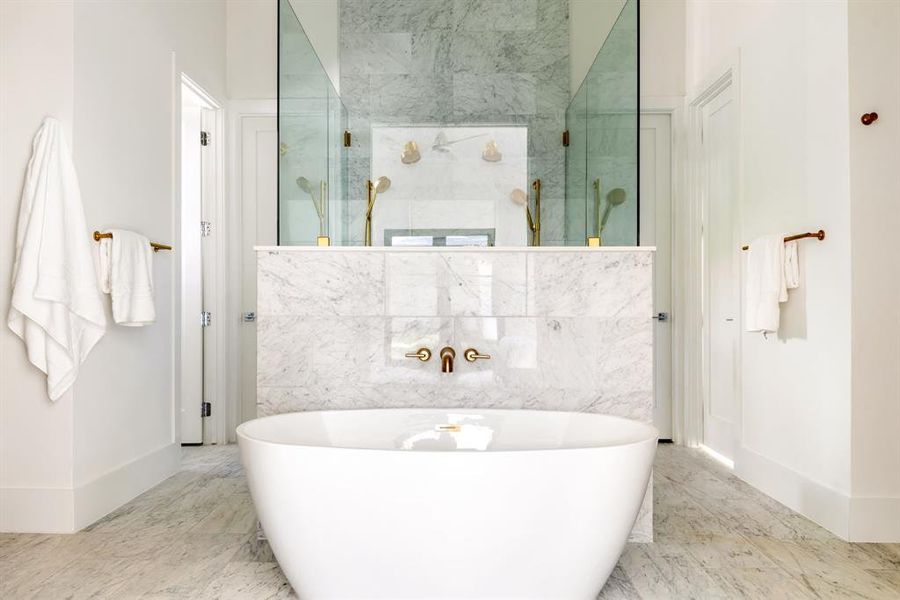 Full bathroom with a freestanding tub, a marble finish shower, and light marble finish floors Full bathroom with a freestanding tub, a marble finish shower, and light marble finish floors
