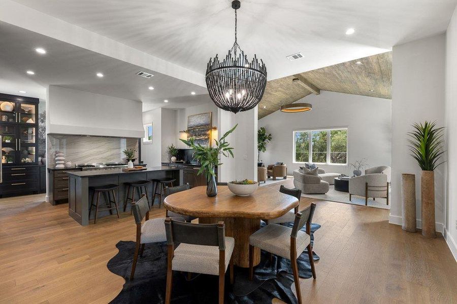 Elegant hardwood flooring extends through this open-concept dining area and living room with a vaulted ceiling.