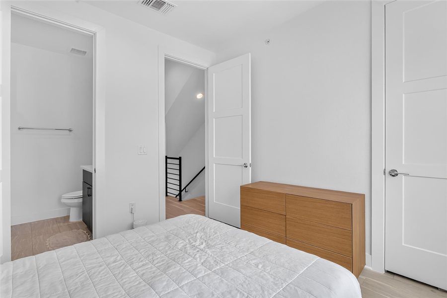 Well-lit sleeping quarters with a dedicated adjacent bathroom and convenient access to stairs.