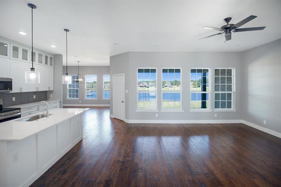 Kitchen featuring appliances with stainless steel finishes, pendant lighting, glass insert cabinets, tasteful backsplash, and dark wood-style floors Kitchen featuring appliances with stainless steel finishes, pendant lighting, glass insert cabinets, tasteful backsplash, and dark wood-style floors