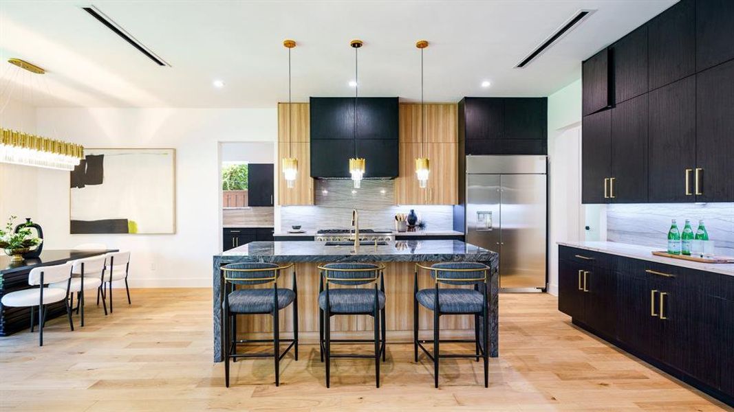 Kitchen with stainless steel built in fridge, a kitchen bar, a center island with sink, and backsplash