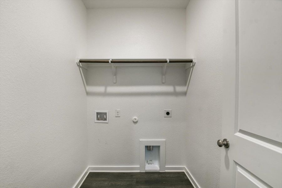 Dedicated laundry area with utility hookups, a built-in shelving system, and wood-finish flooring