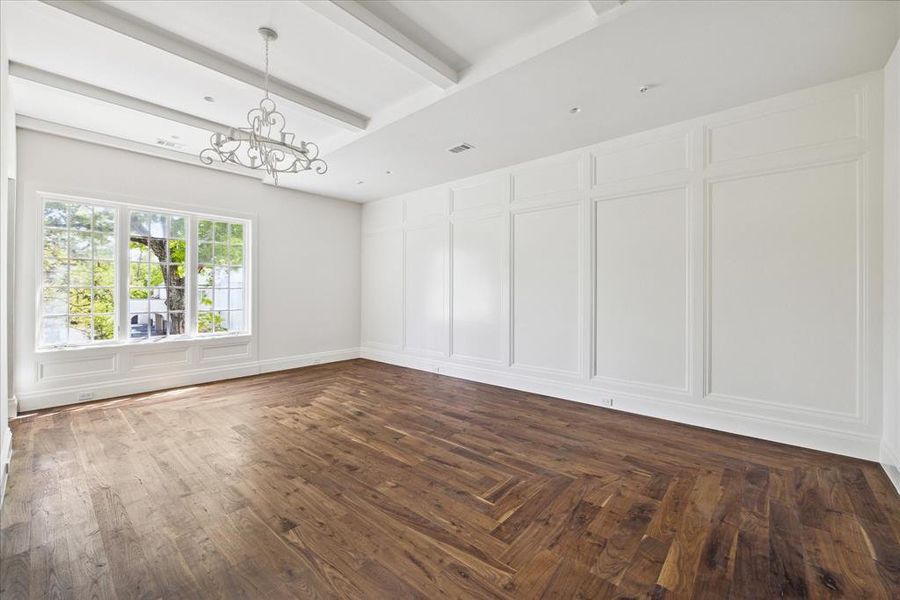 This secondary bedroom features raised ceilings with a chandelier and wood beams, wood paneling, an en-suite bathroom, and walk-in closet.