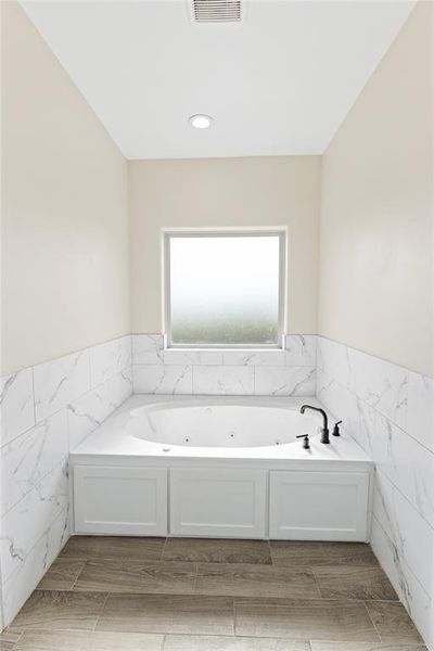 Bathroom featuring tile patterned flooring, a tub, and tile walls