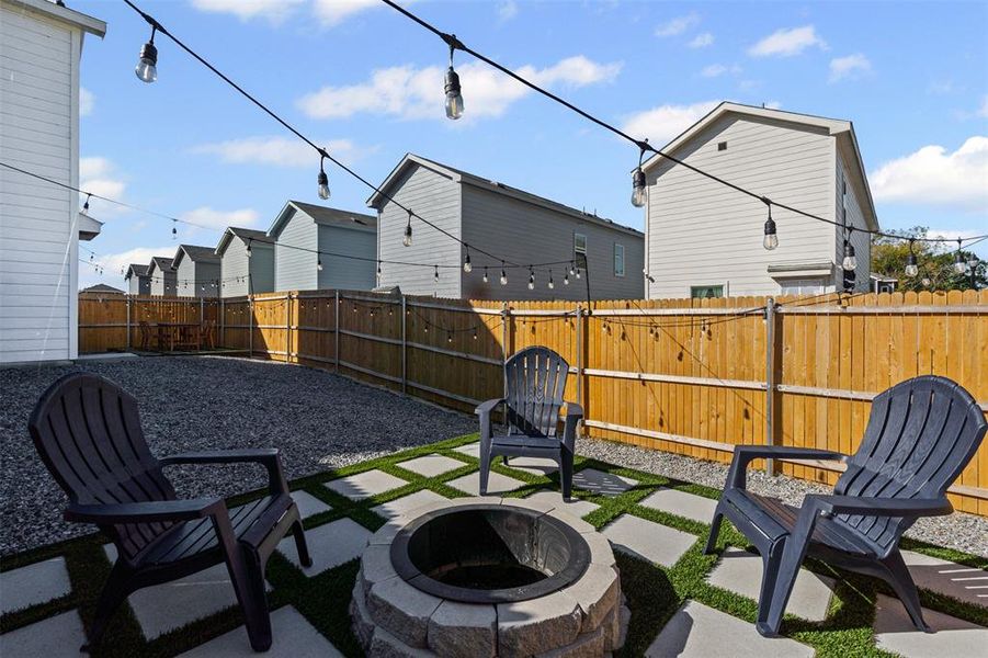 Fenced backyard featuring a fire pit, a patio area, and a residential view