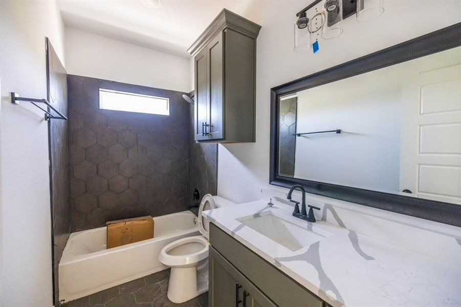 Full bathroom featuring vanity, tiled shower / bath, toilet, and tile patterned flooring