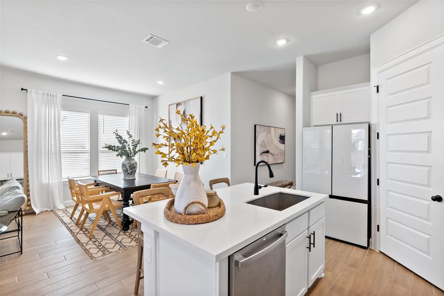 Kitchen with white cabinets, freestanding refrigerator, recessed lighting, stainless steel dishwasher, and light wood-type flooring