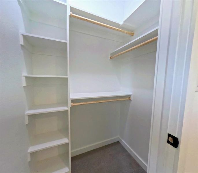 Walk in closet featuring dark carpet Walk in closet featuring dark carpet