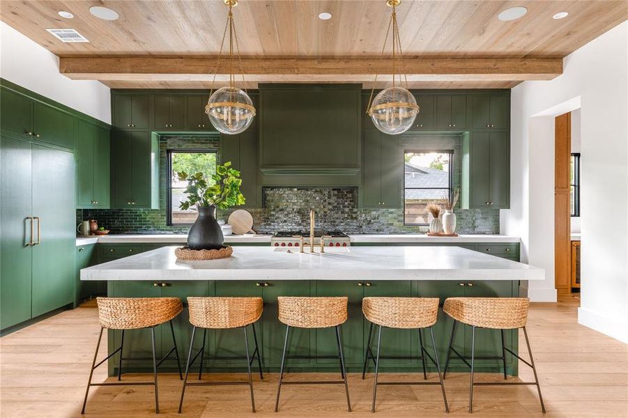Kitchen with green cabinets, a chandelier, a wood ceiling with exposed beams, light countertops, and wall chimney range hood