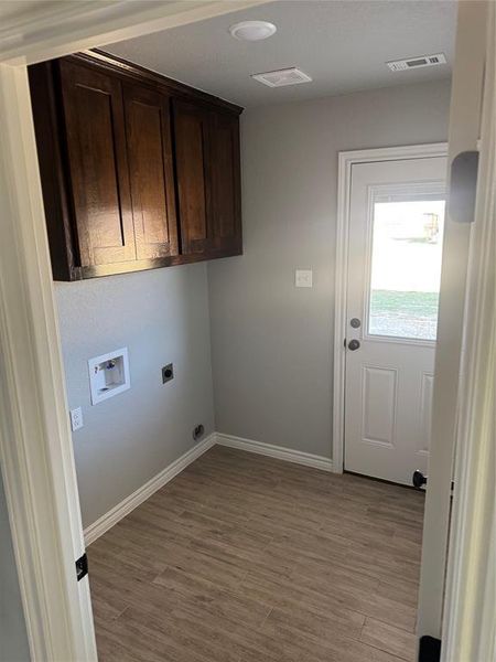 Washroom featuring electric dryer hookup, cabinets, washer hookup, and light hardwood / wood-style flooring